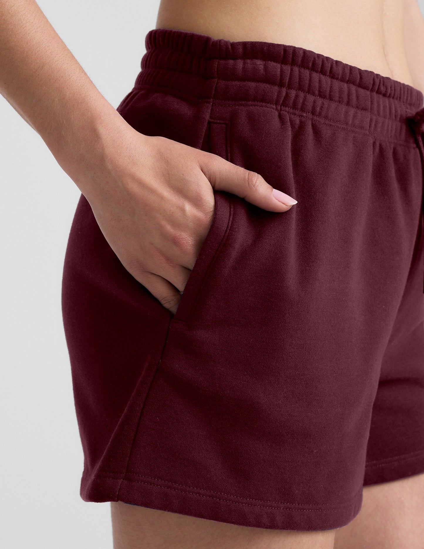 Close-up of burgundy LuxeFleece Sweat Short showing soft fleece, elastic waistband, and hand tucked into the side pocket.