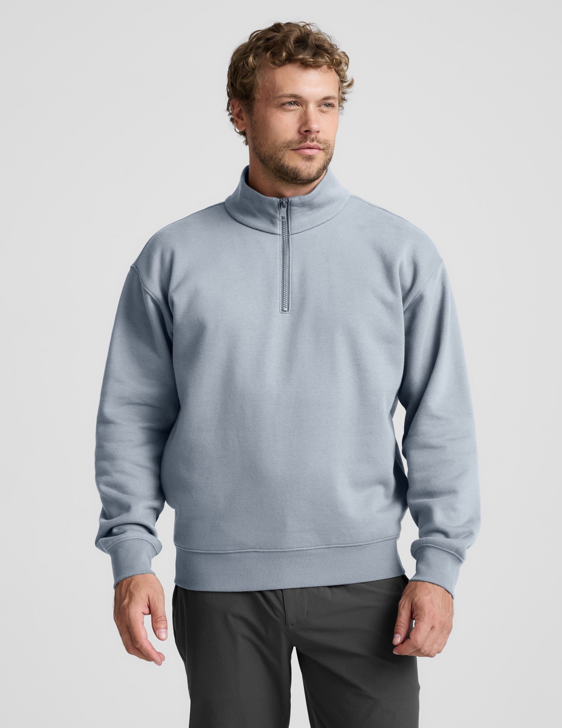 Man wearing a light blue half-zip sweatshirt against a plain background.