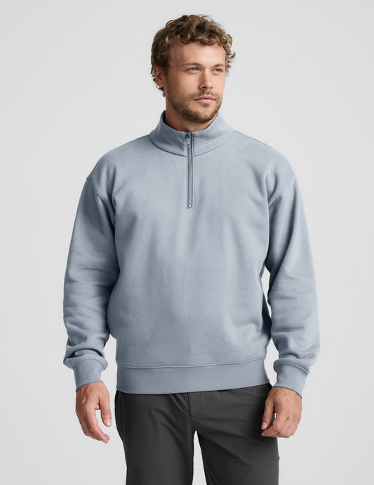 Man wearing a light blue half-zip sweatshirt against a plain background.