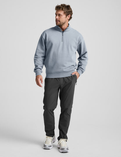 Man wearing a light blue half-zip sweatshirt against a plain background.