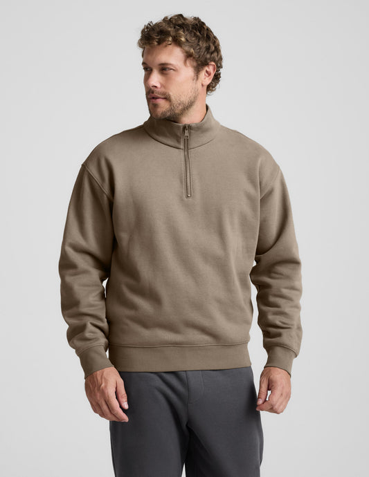 Man wearing a brown half-zip sweatshirt against a light gray background.