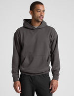 Man wearing a gray hoodie and pants on a light gray background.