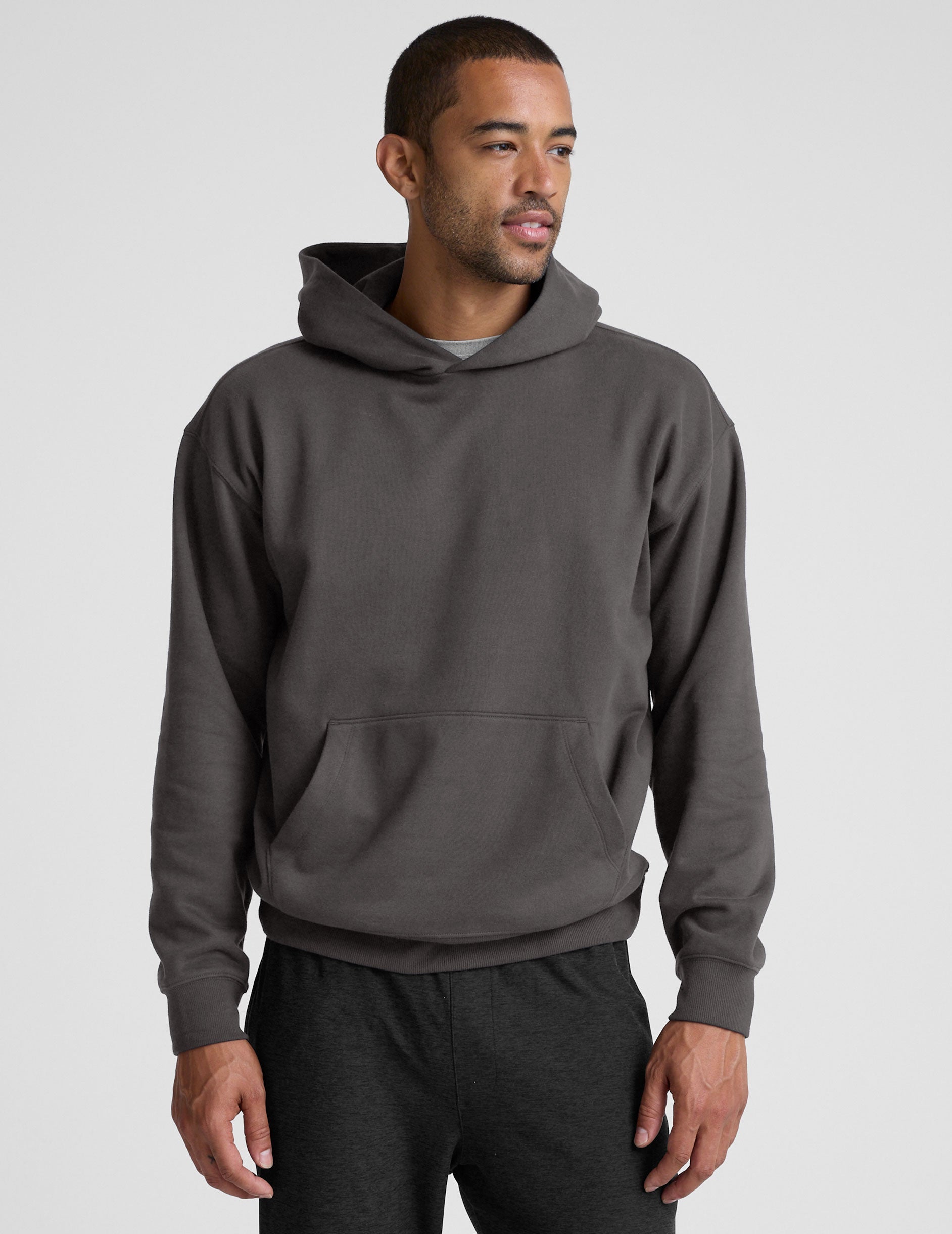 Man wearing a gray hoodie and pants on a light gray background.