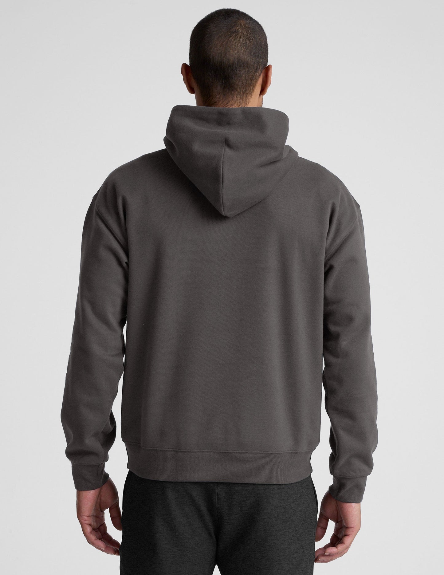 Man wearing a gray hoodie and pants on a light gray background.