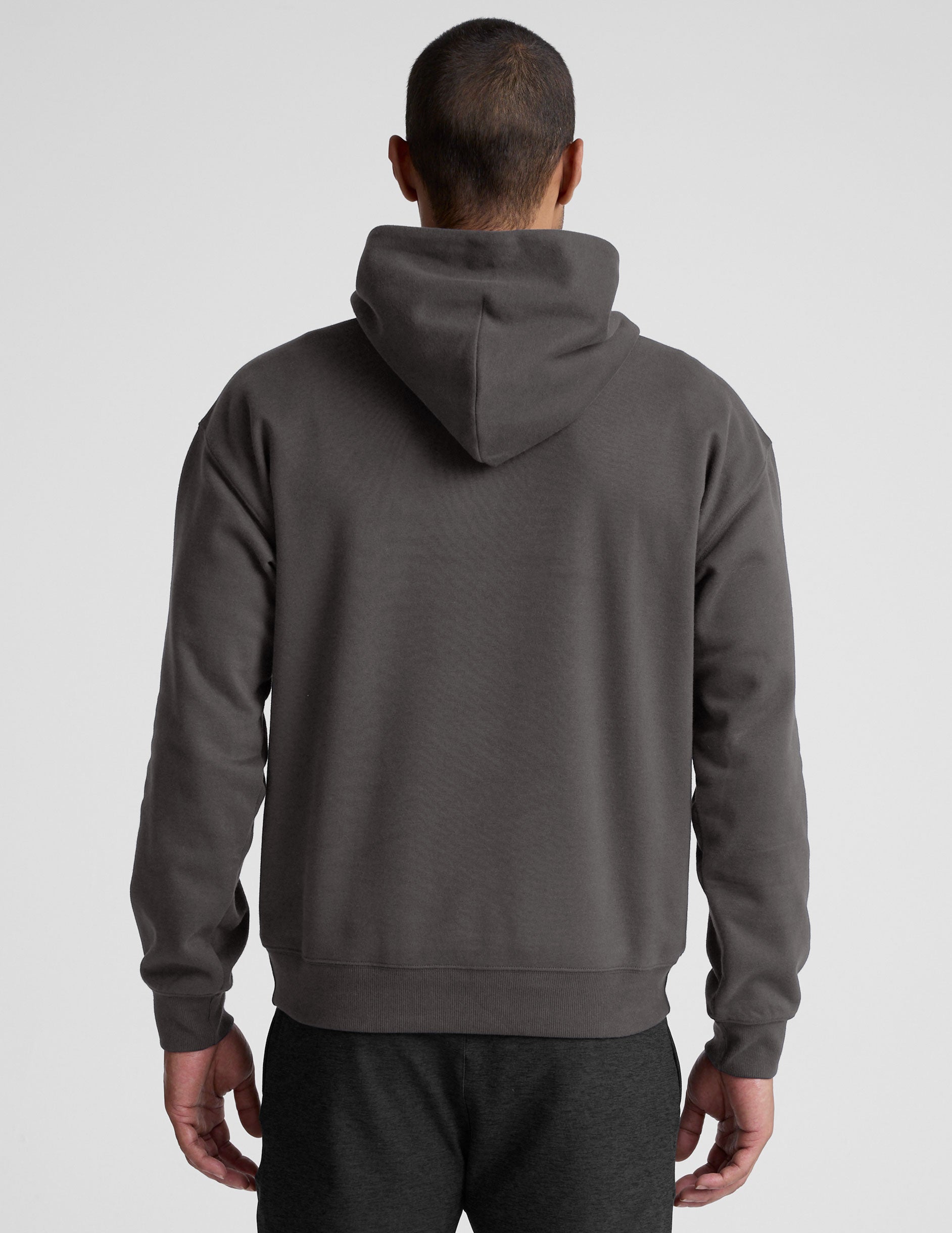 Man wearing a gray hoodie and pants on a light gray background.