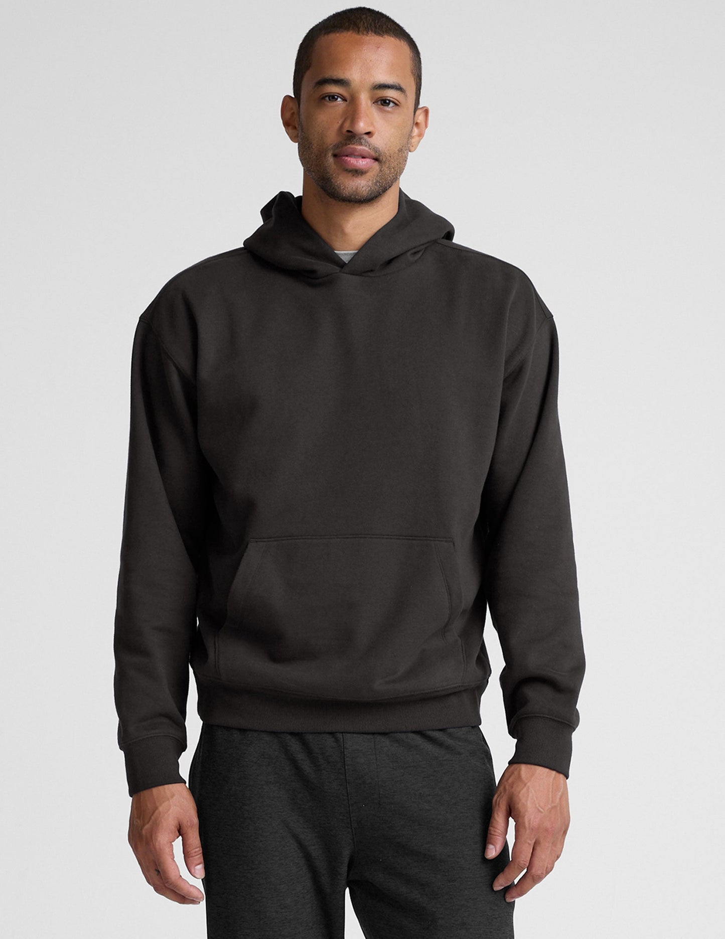 man wearing a black hoodie on a plain background.