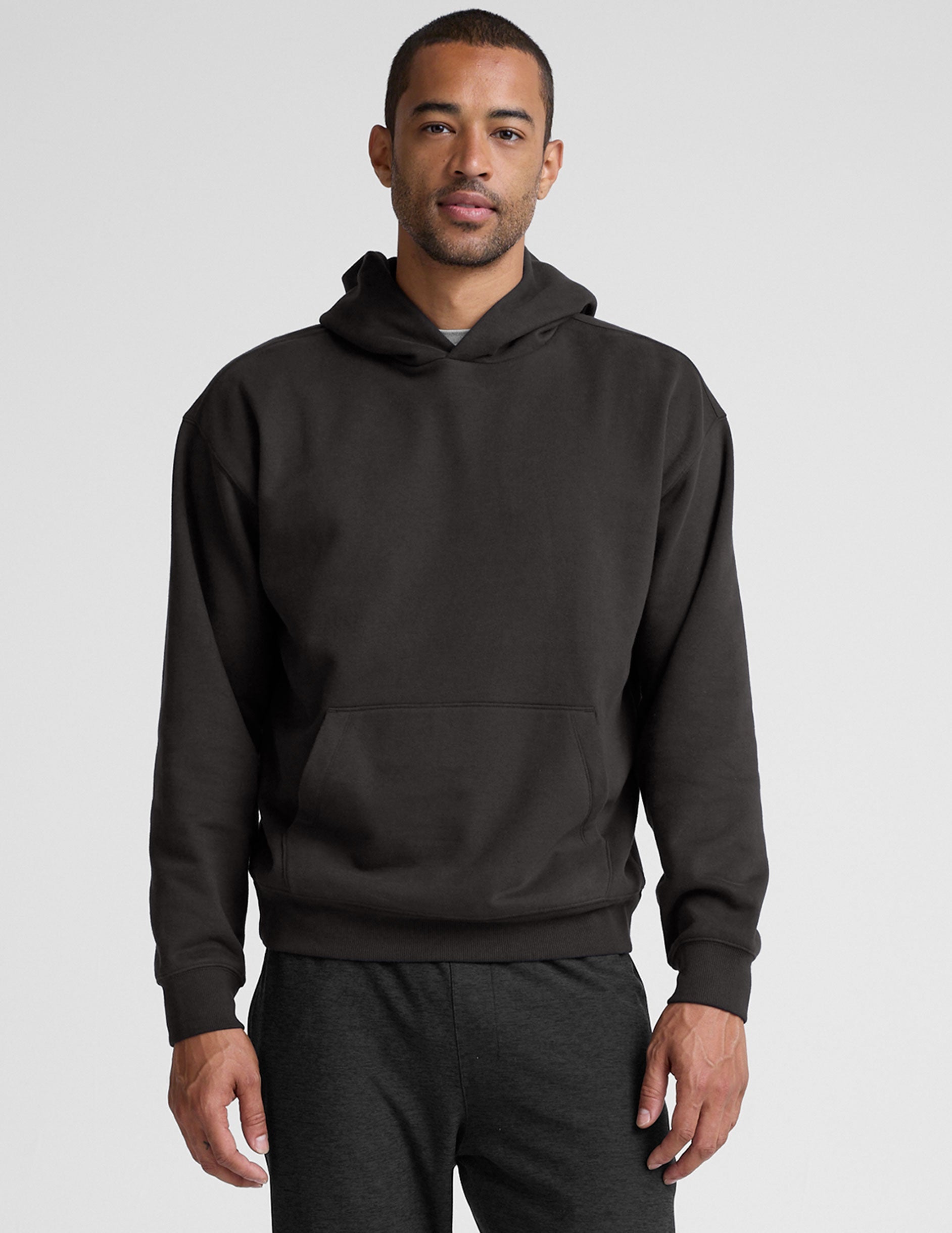 man wearing a black hoodie on a plain background.