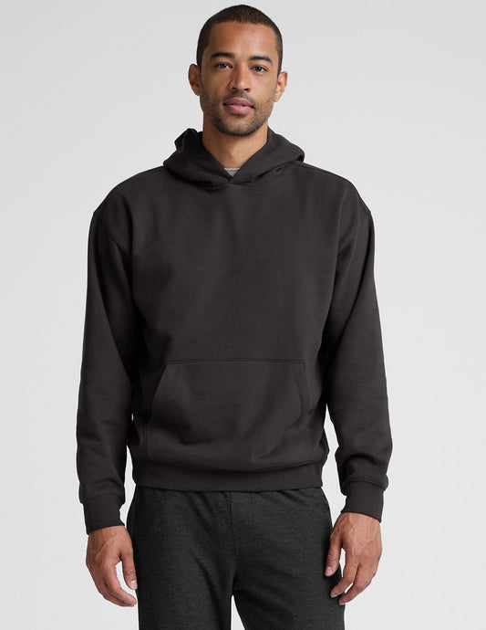 man wearing a black hoodie on a plain background.