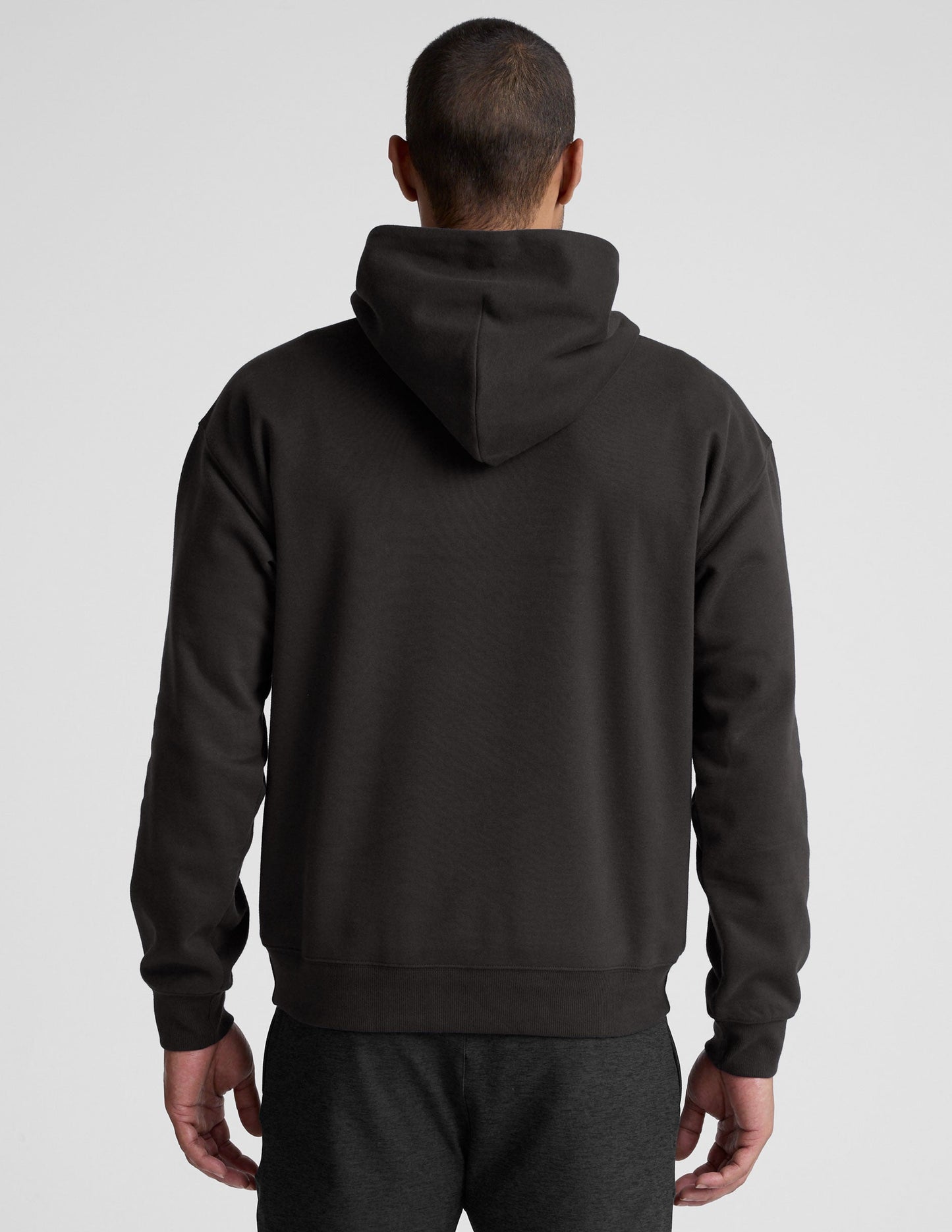 man wearing a black hoodie on a plain background.