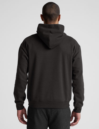 man wearing a black hoodie on a plain background.