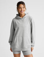 Woman wearing a gray hoodie and shorts set on a light gray background.