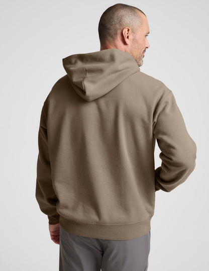 Man wearing a brown hoodie on a plain background.