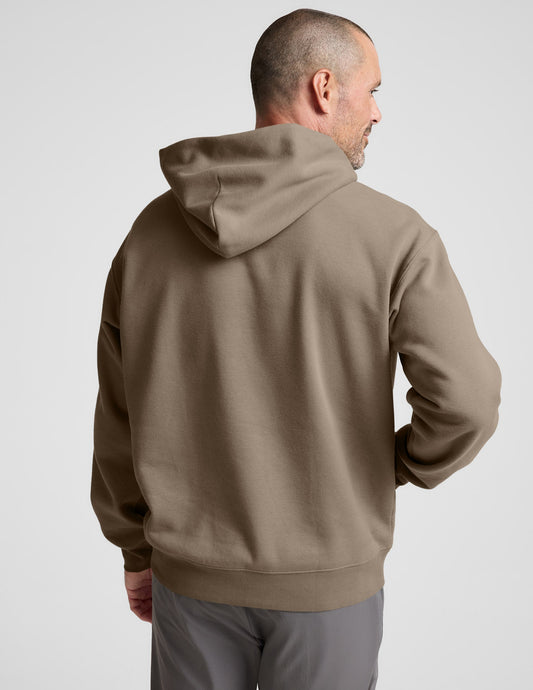 Man wearing a brown hoodie on a plain background.