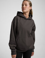 Woman wearing a dark brown hoodie on a light gray background