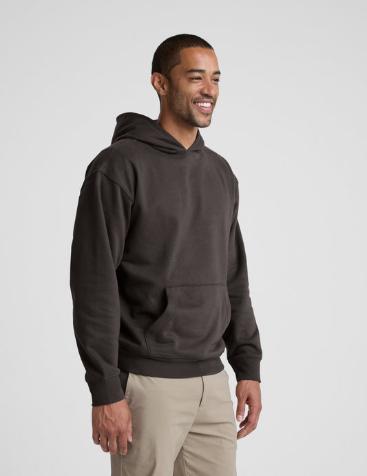 Man wearing a dark brown hoodie on a light gray background