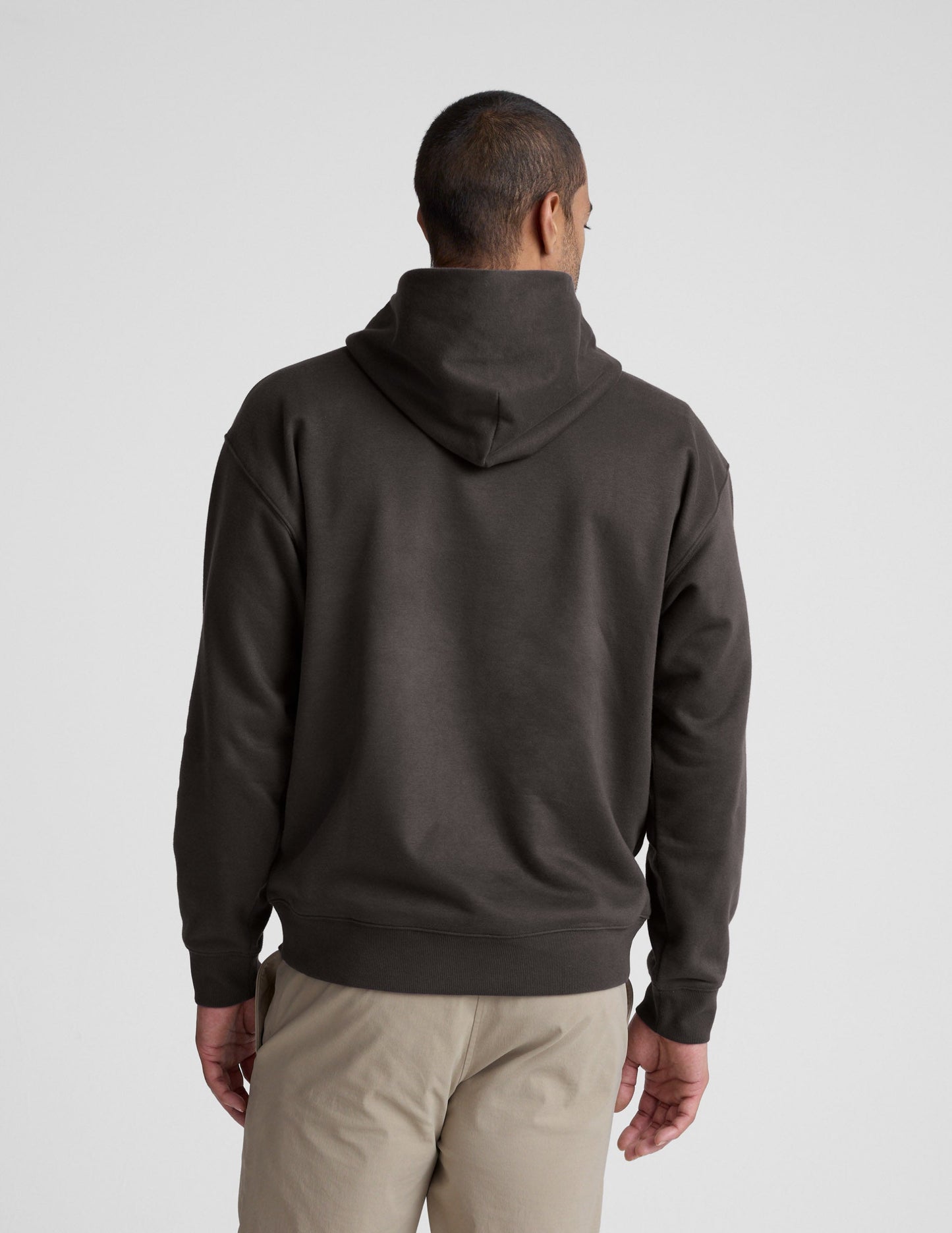 Man wearing a dark brown hoodie on a light gray background