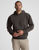 Man wearing a dark brown hoodie on a light gray background