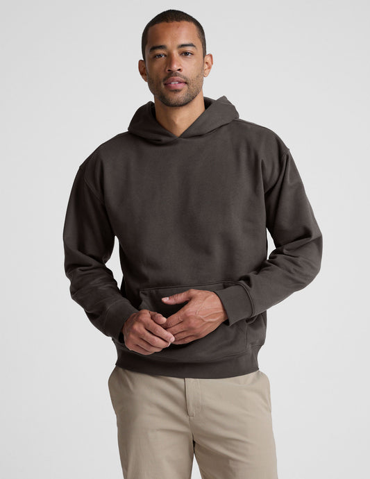Man wearing a dark brown hoodie on a light gray background