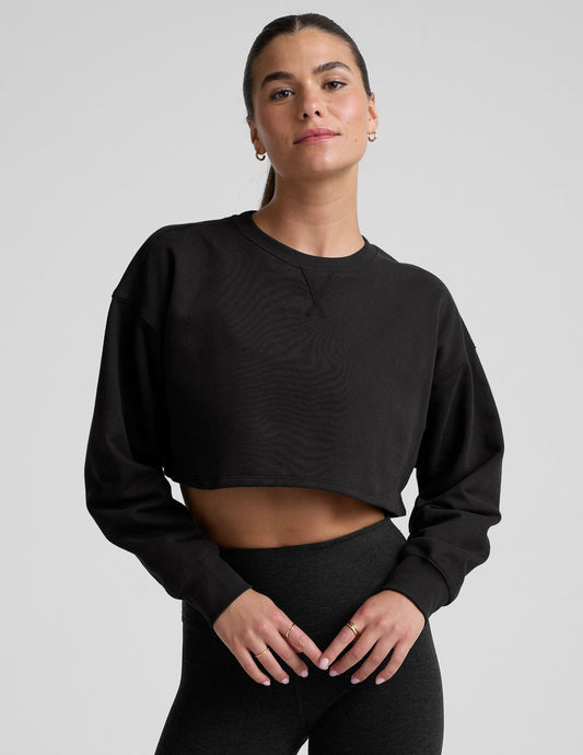 model wearing a black boxy fit cropped sweatshirt against a plain background.