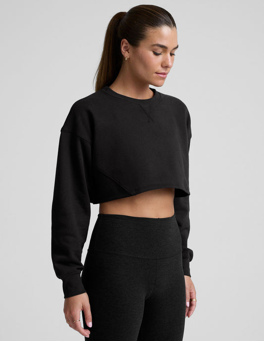 model wearing a black boxy fit cropped sweatshirt against a plain background.