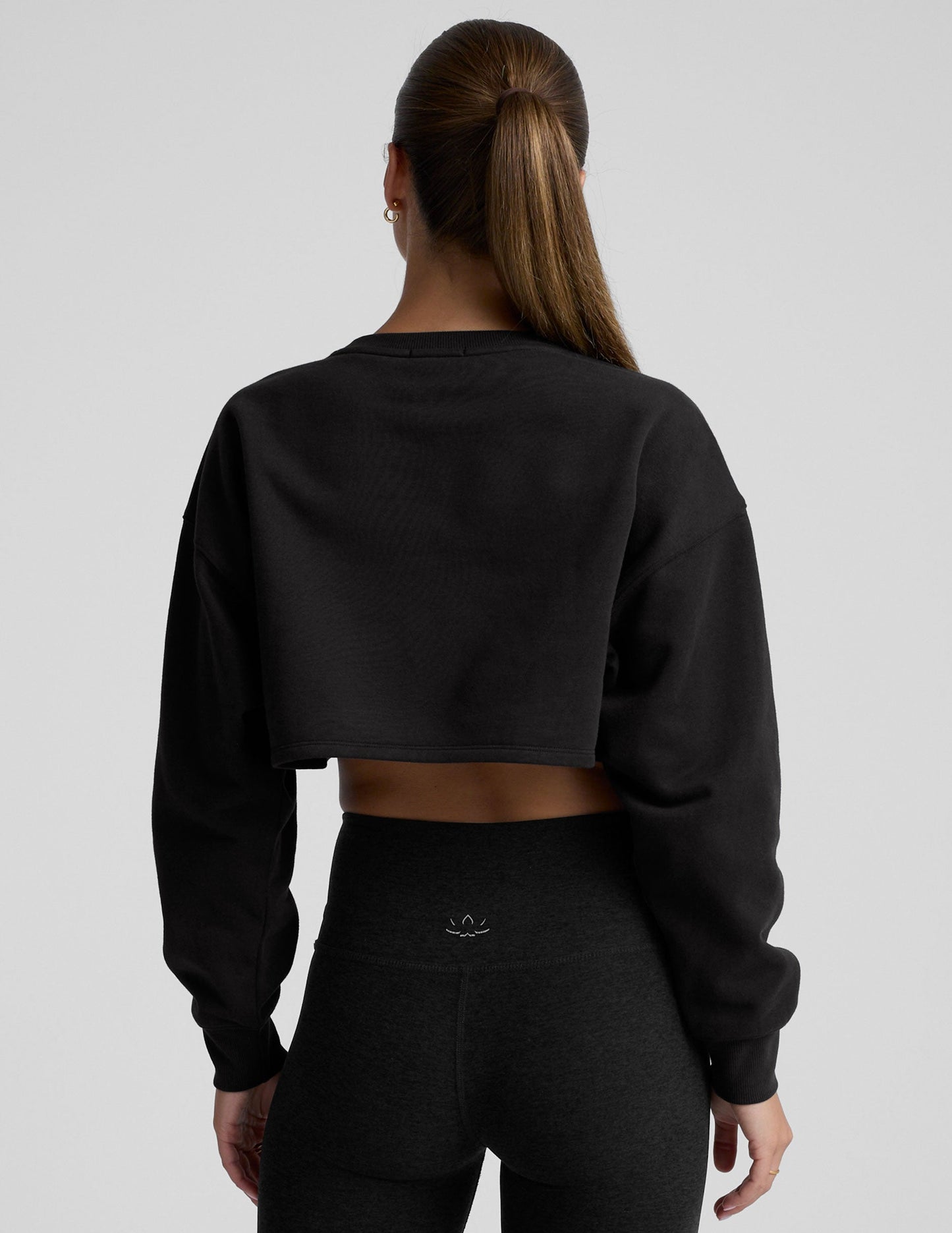 model wearing a black boxy fit cropped sweatshirt against a plain background.