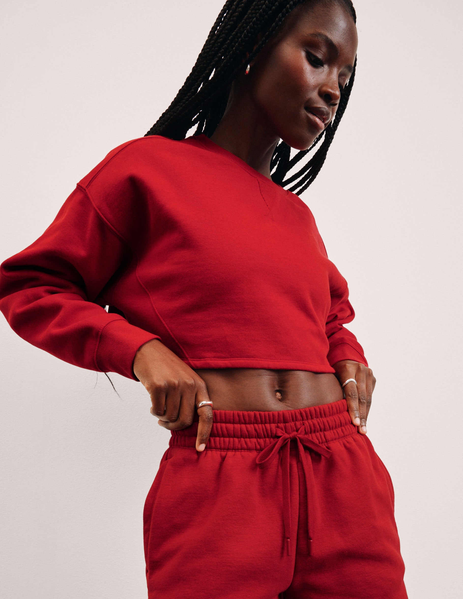 Person wearing a red sweatshirt and pants on a light pink background.