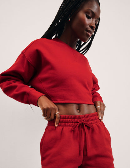Person wearing a red sweatshirt and pants on a light pink background.