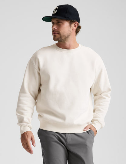 Man wearing a white sweatshirt and gray pants against a plain background.