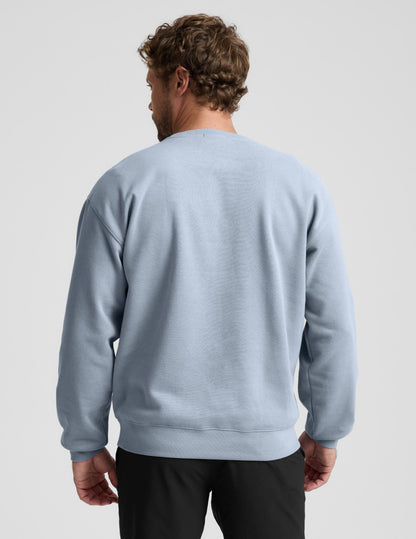 Man wearing a light blue sweatshirt on a plain background.