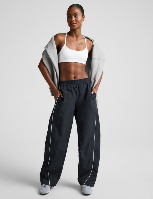 Front view of Limitless Mid-Rise Barrel Leg Pant in gray with white piping and a gathered elastic waistband on a model.