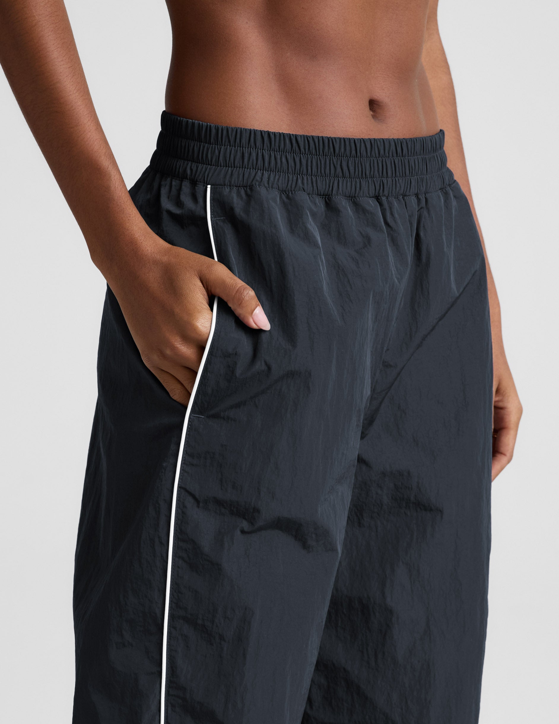 Gray Limitless Mid-Rise Barrel Leg Pant featuring a gathered elastic waistband, side pocket, and contrast white piping detail.