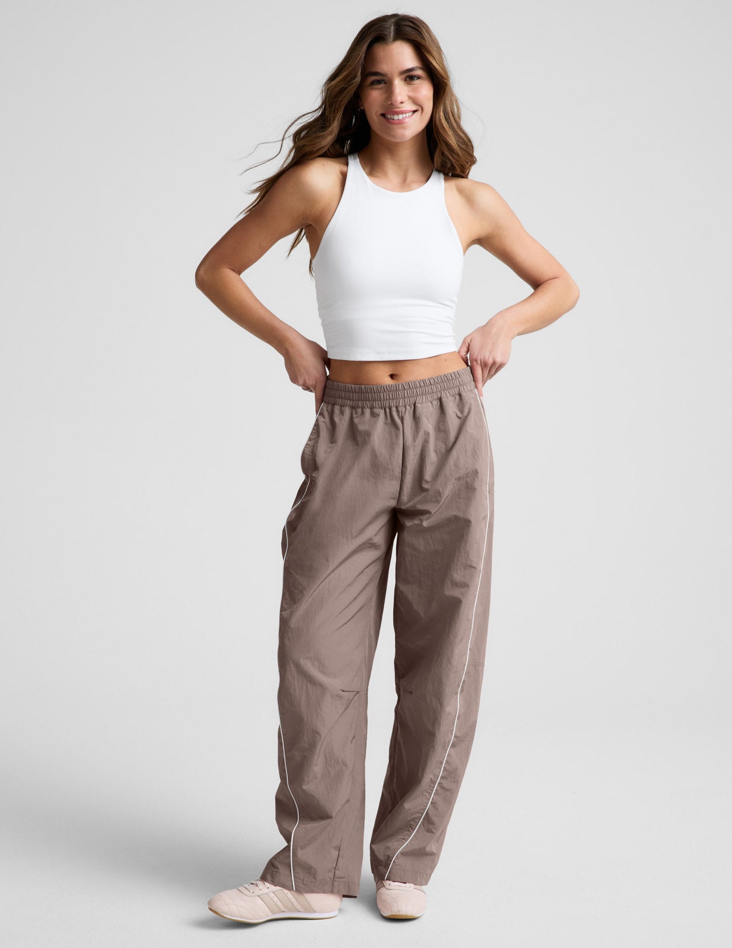 Brown Limitless Mid-Rise Barrel Leg Pant with white side piping and an elastic waist on a model in a white tank top.