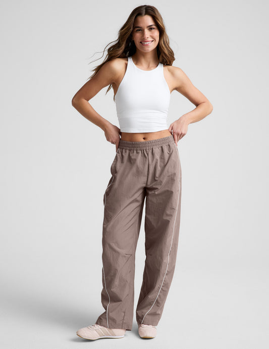 Brown Limitless Mid-Rise Barrel Leg Pant with white side piping and an elastic waist on a model in a white tank top.