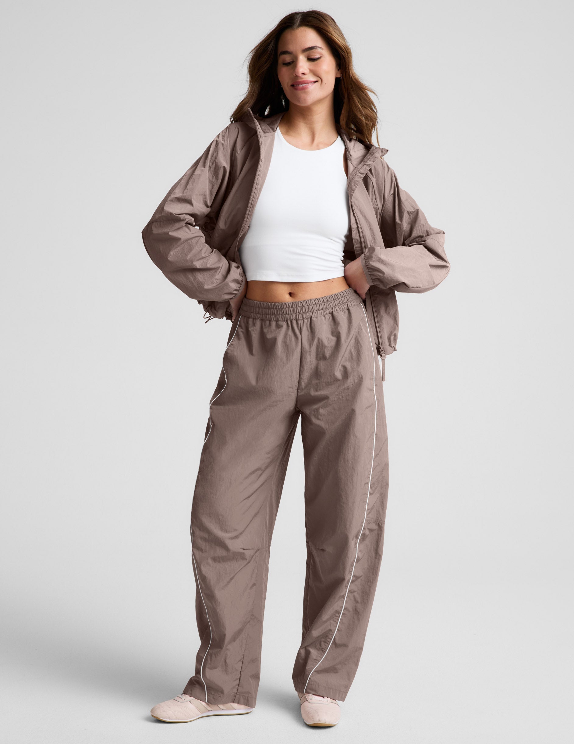 Limitless Mid-Rise Barrel Leg Pant in brown with white piping and elastic waistband on a model in a matching jacket.