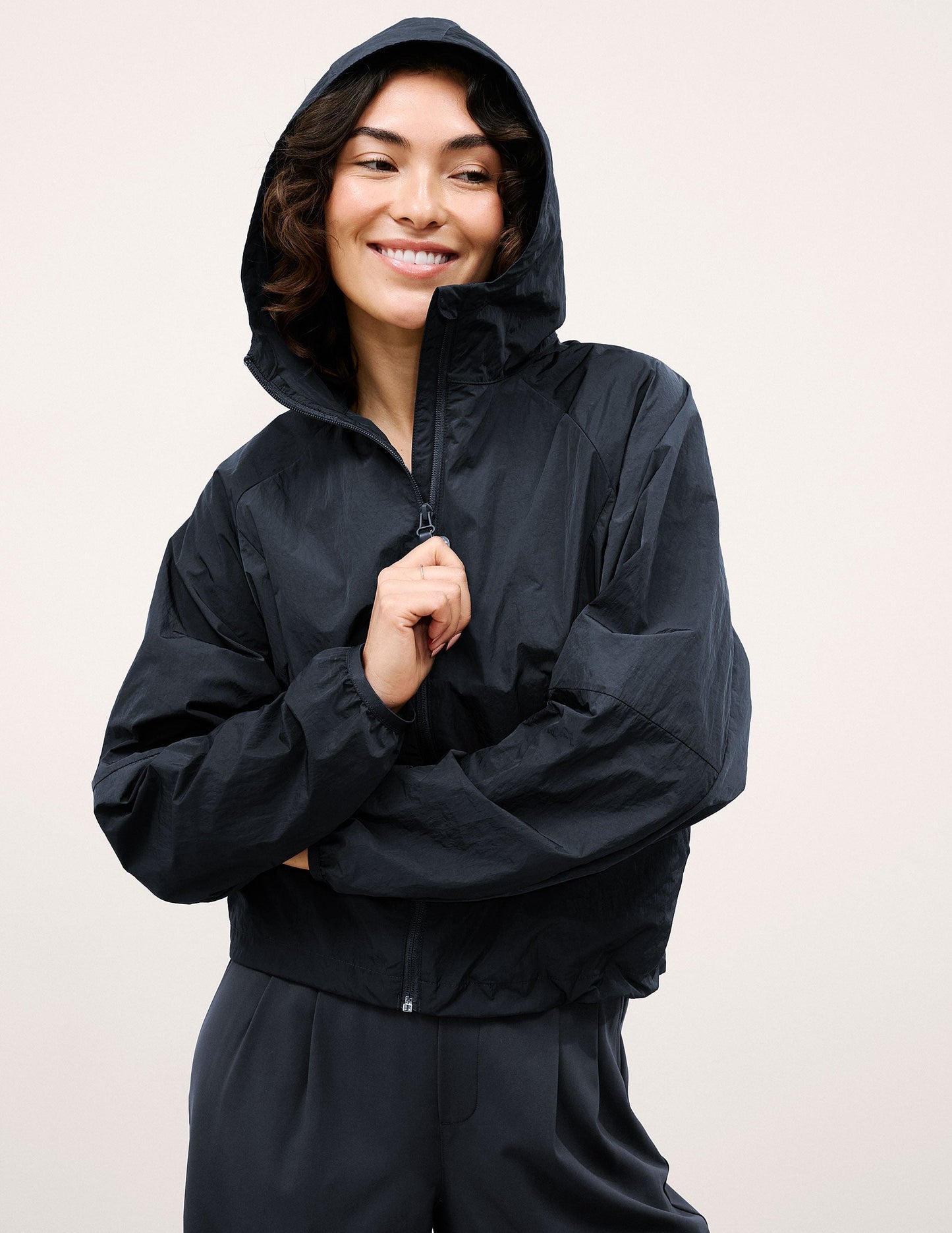 Woman wearing a blue hooded jacket and pants against a plain background.