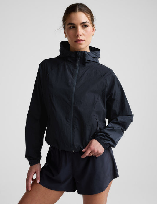 Woman wearing a blue hooded jacket and shorts against a plain background.