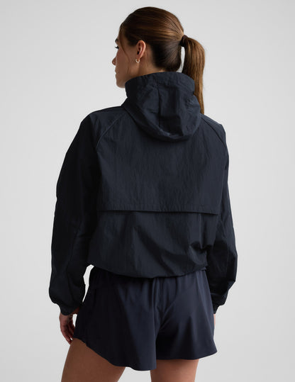 Woman wearing a blue hooded jacket and shorts against a plain background.