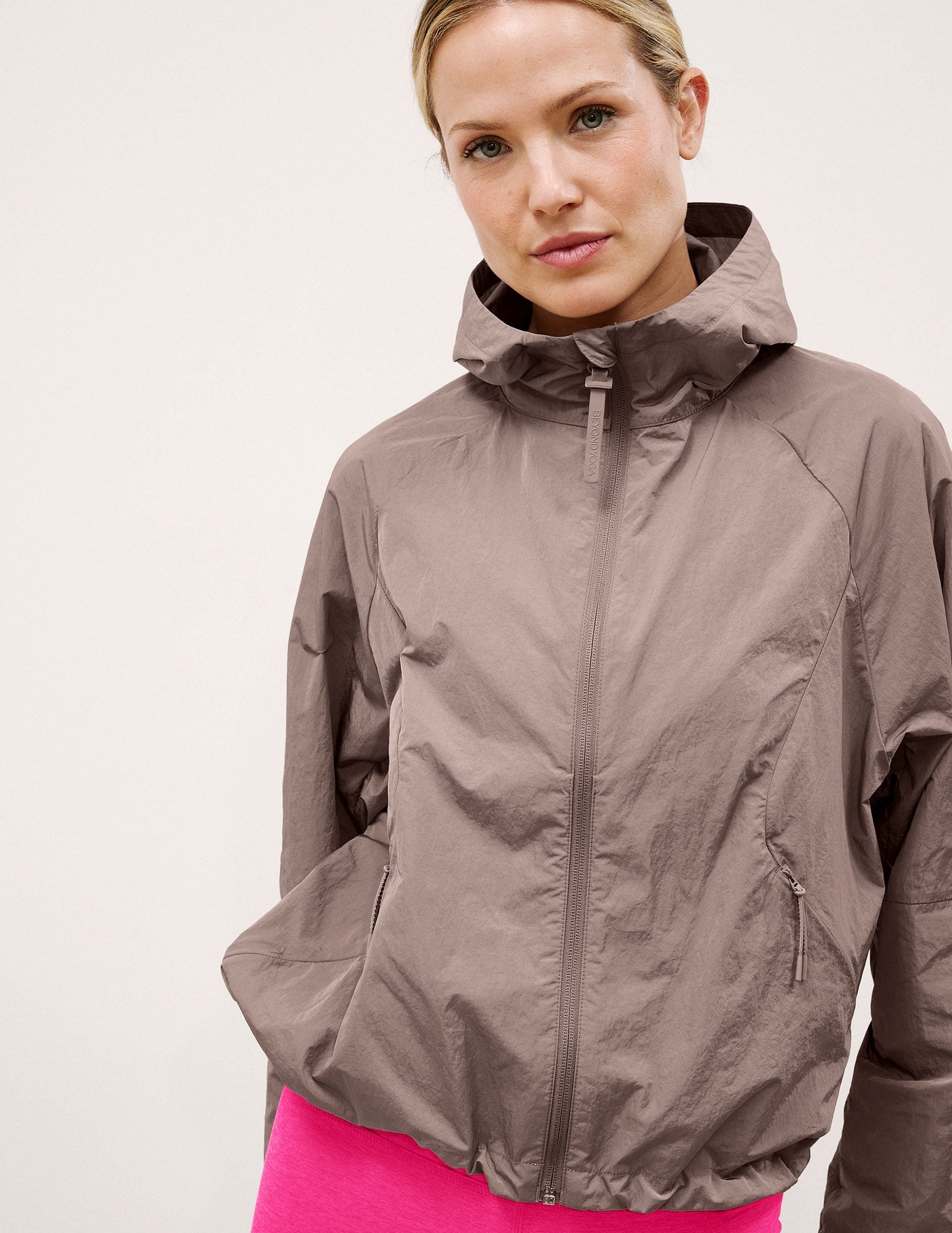 Woman wearing a brown hooded jacket on a light background.