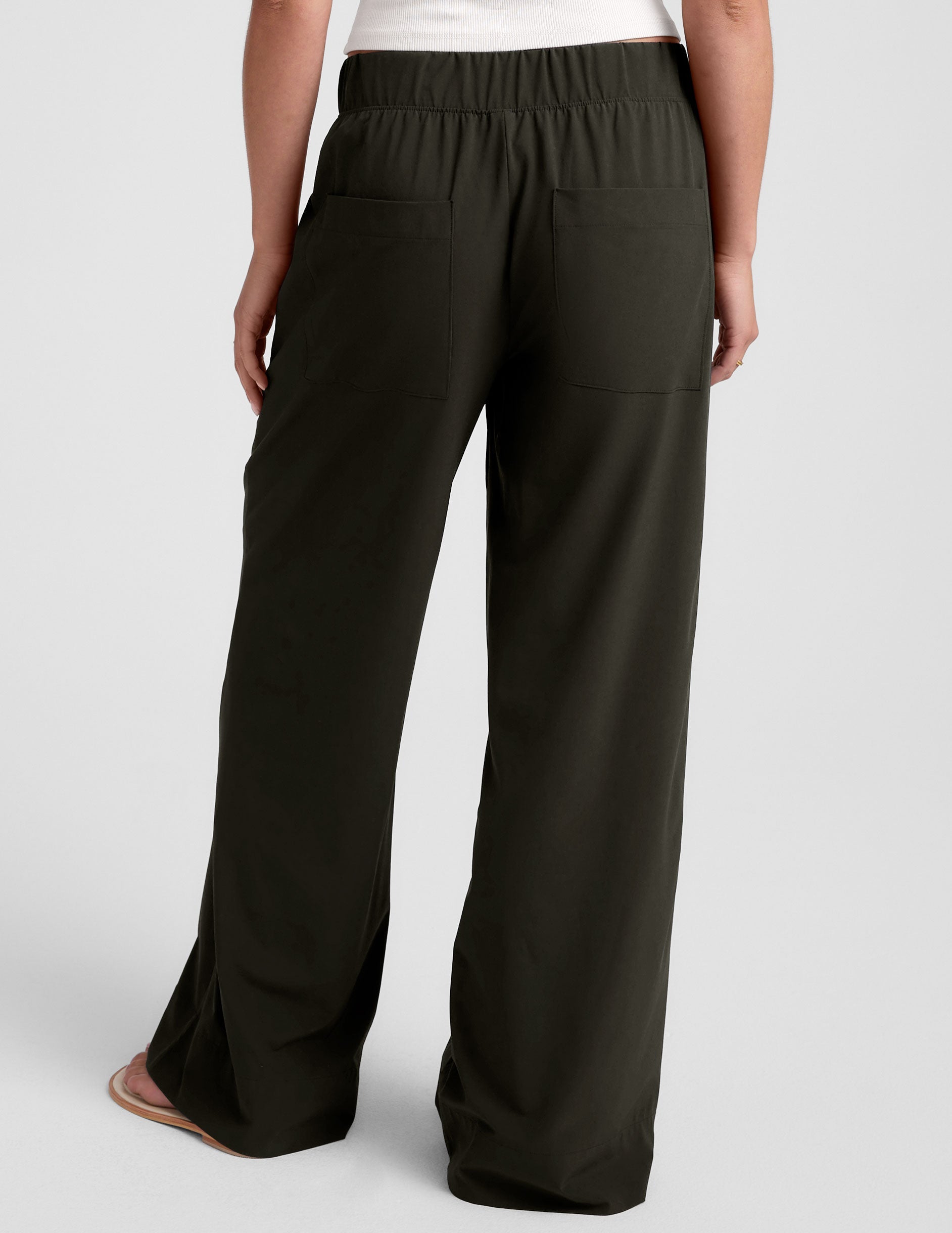 Rear view of a person wearing the Easy Wide Leg Pant in dark green with an elastic waistband and two large back pockets.