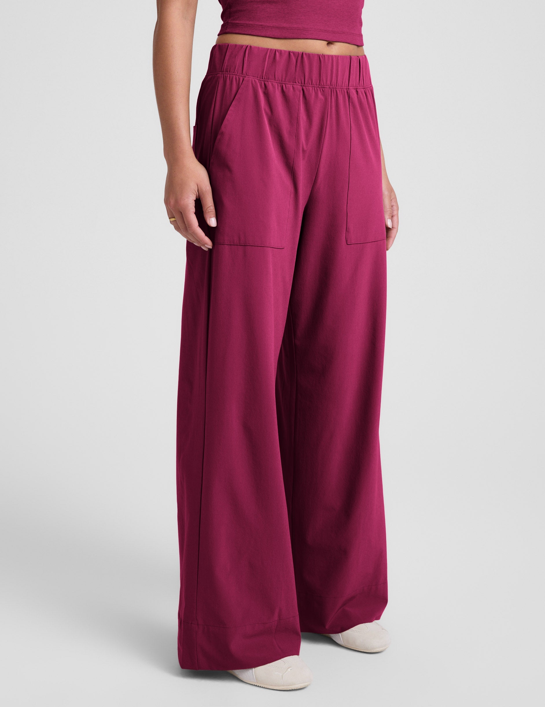 Woman wearing Maroon Beyond Yoga™ Easy Wide Leg Pant 31" paired with a matching crop top and cream sneakers.