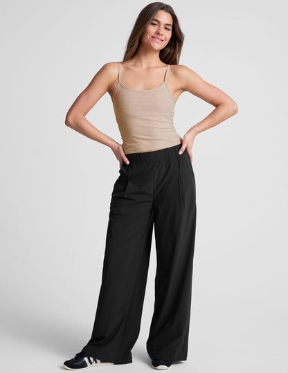 Smiling woman wears black Easy Wide Leg 29" Pant with a relaxed fit, pleated front, and gathered elastic waistband.