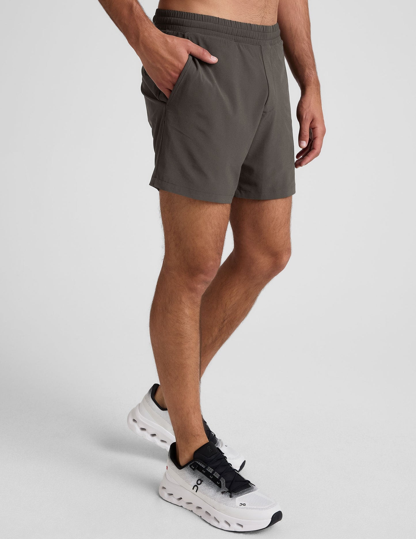 Side view of a man wearing Pivotal 2.0 Men's Lined Shorts in dark gray, featuring side pockets and an elastic waistband.