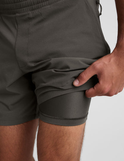 Gray Pivotal 2.0 Men's Lined Short 7" featuring a gathered elastic waist and a hand lifting the hem to reveal the liner.