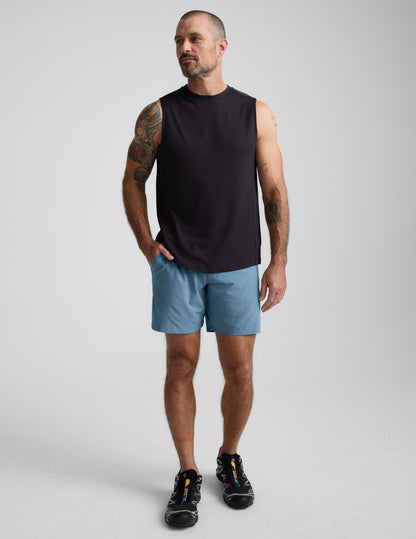 Man wearing blue Pivotal 2.0 Men's Lined Short 7" with elastic waistband and side pockets, standing in a studio.