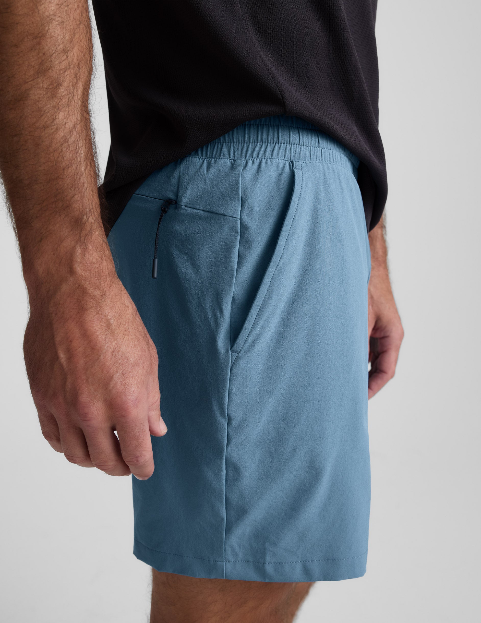 Side view of blue Pivotal 2.0 Men's Lined Short 7" with elastic waist, side hand pocket, and hidden zipper pocket.