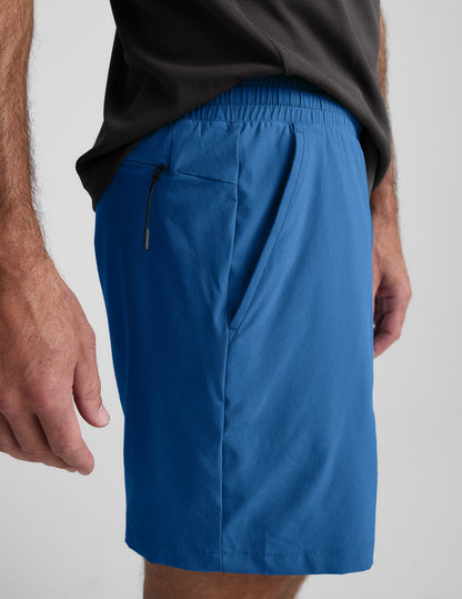 Side profile of man wearing blue Pivotal 2.0™ Men's Lined Short 7" with a grey t-shirt and hidden zipper pocket.