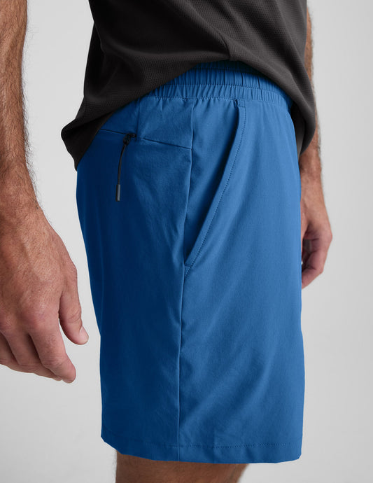 Side profile of man wearing blue Pivotal 2.0™ Men's Lined Short 7" with a grey t-shirt and hidden zipper pocket.