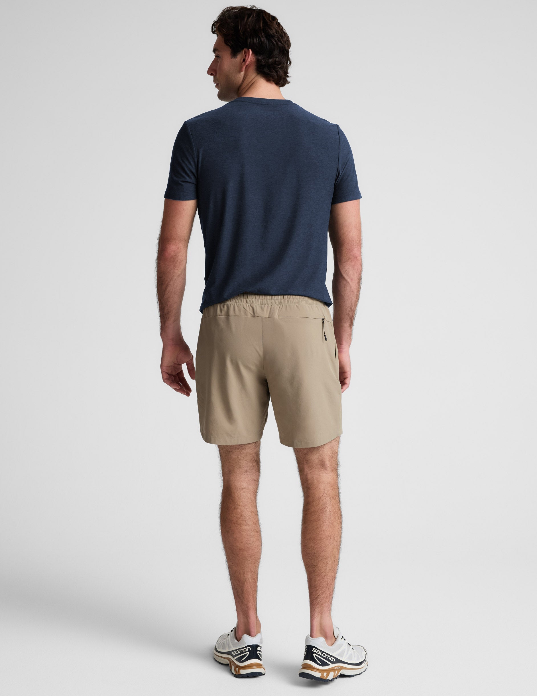 Rear view of a man wearing beige Pivotal 2.0 Men's Lined Short 7" with an elastic waist and back zipper pocket.