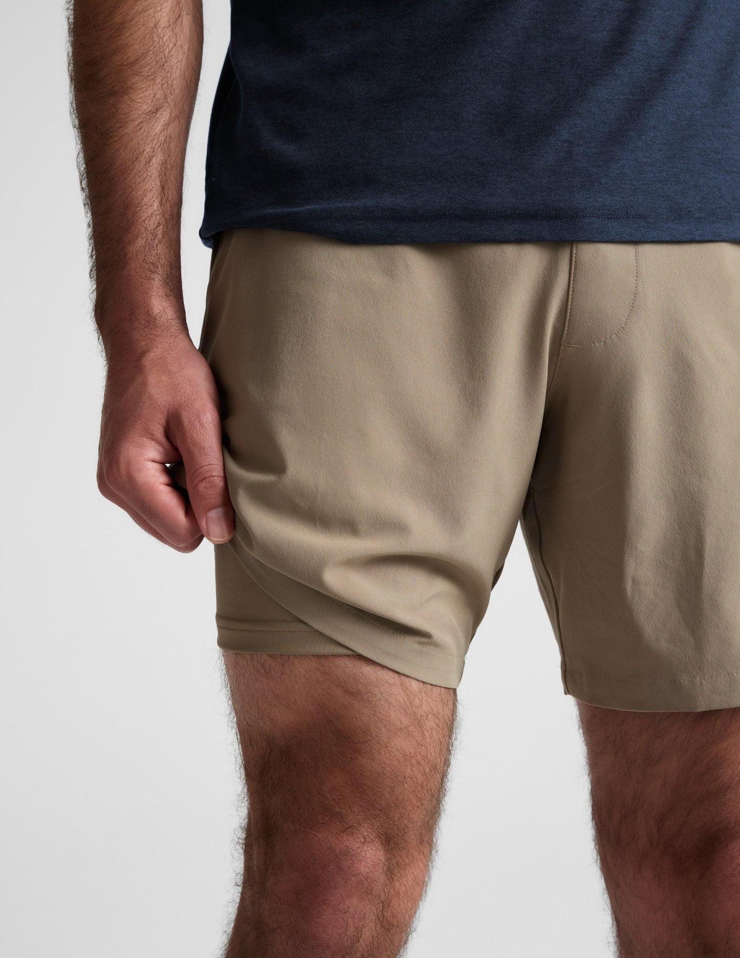 Close-up of beige Pivotal 2.0 Men's Lined Short 7" showing the lightweight fabric and built-in liner on a man.