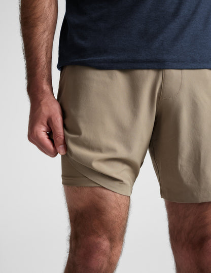 Close-up of beige Pivotal 2.0 Men's Lined Short 7" showing the lightweight fabric and built-in liner on a man.